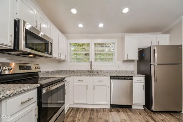 a kitchen with stainless steel appliances granite countertop white cabinets a microwave a sink and a refrigerator