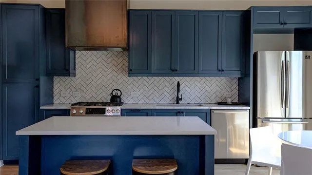 a kitchen with stainless steel appliances a sink a stove a refrigerator and cabinets