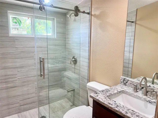 a bathroom with a granite countertop sink toilet and shower