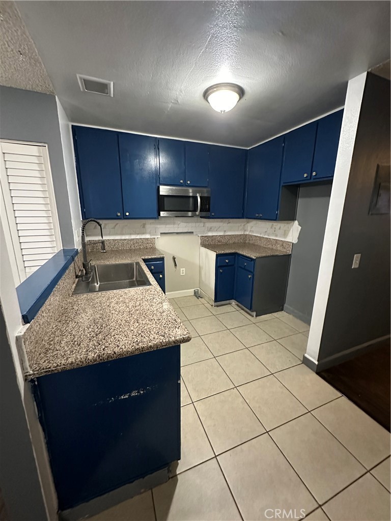 165 Racquet Club Drive Compton, CA 90220 - Photo 13 of 47 a kitchen with a sink a stove a microwave and cabinets