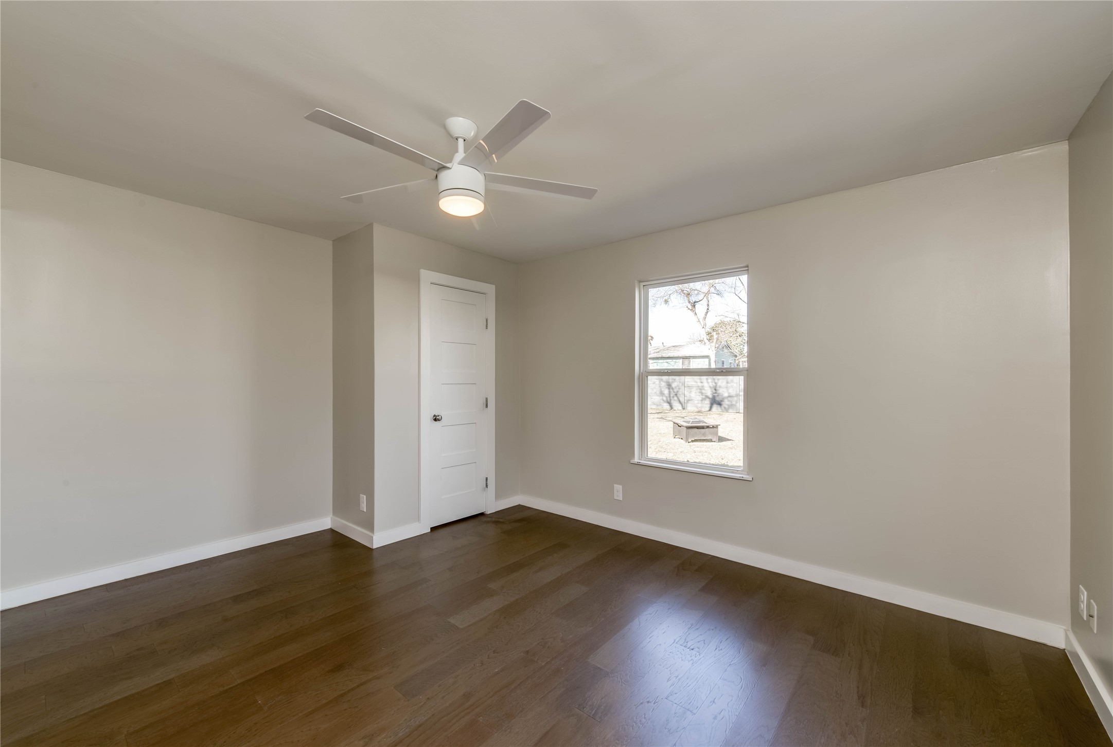 4702 Bandera Road Austin, TX 78721 - Photo 7 of 12 a view of an empty room with wooden floor and a window