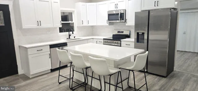 a kitchen with stainless steel appliances a table chairs microwave and refrigerator