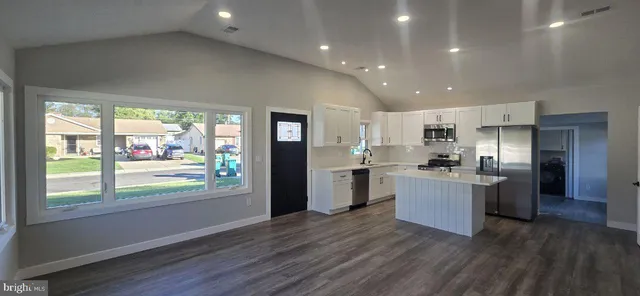 a kitchen with stainless steel appliances kitchen island wooden floors and large window