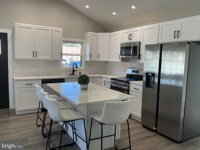 a kitchen with stainless steel appliances a dining table chairs refrigerator and microwave