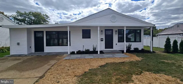 a front view of a house with a garden and chairs