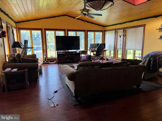 a living room with furniture a flat screen tv and floor to ceiling window