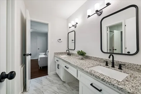 a bathroom with a granite countertop sink vanity and mirror