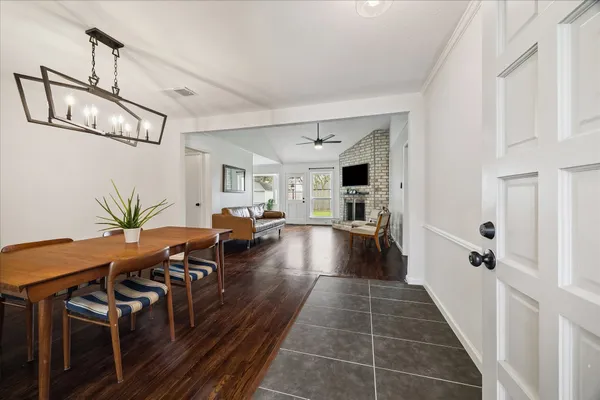 a view of a hallway with couches and dining table with wooden floor
