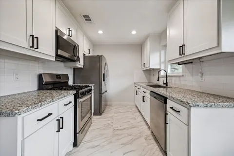 a kitchen with stainless steel appliances granite countertop a sink stove refrigerator and cabinets