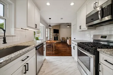 a kitchen with stainless steel appliances granite countertop a stove a sink and a microwave