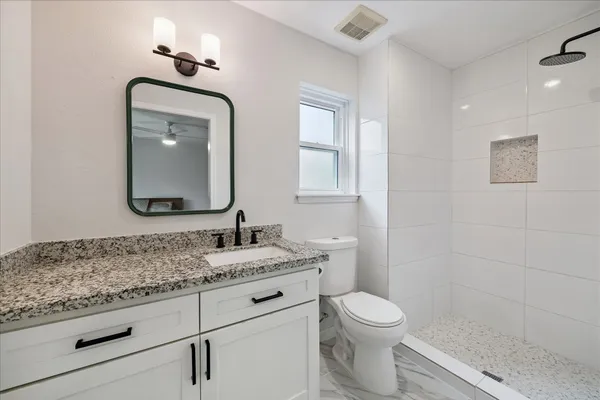 a bathroom with a granite countertop toilet sink and mirror