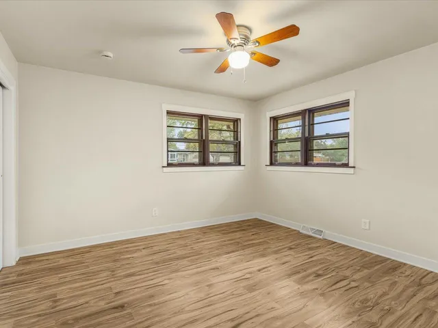 a view of an empty room with a window and wooden floor