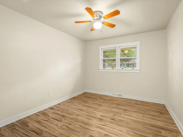 an empty room with a window and a ceiling fan
