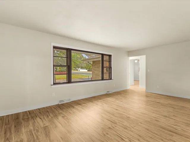 an empty room with wooden floor and windows