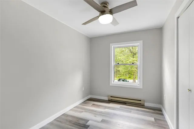 an empty room with windows and fan