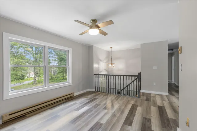 a view of a room with wooden floor fan and windows