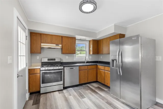 a kitchen with stainless steel appliances granite countertop a stove a sink and a refrigerator