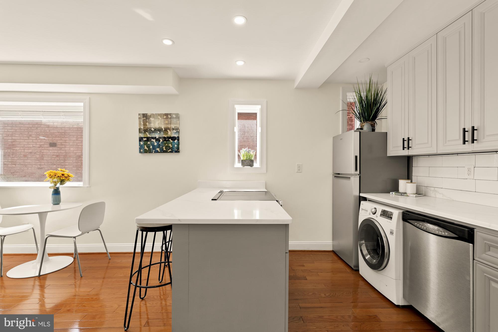 1125 12th Street Northwest, Unit 31 Washington, DC 20005 - Photo 14 of 25 a utility room with stainless steel appliances wooden floor dining table and chairs