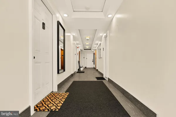 a view of a hallway with wooden floor and a bathroom