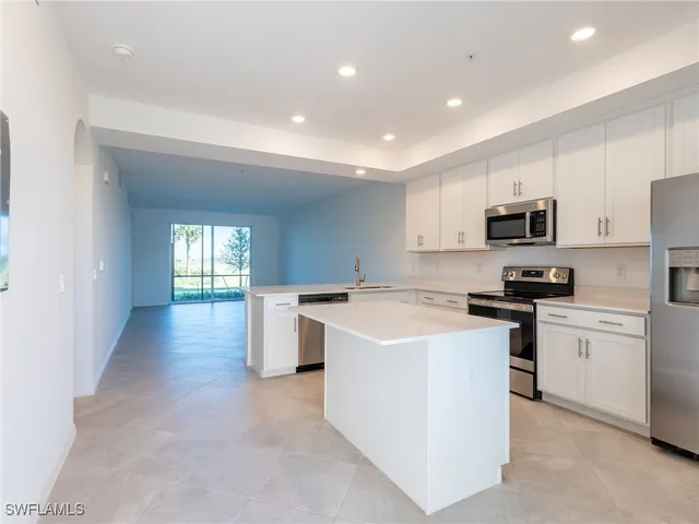 a large kitchen with a large counter top a sink and stainless steel appliances