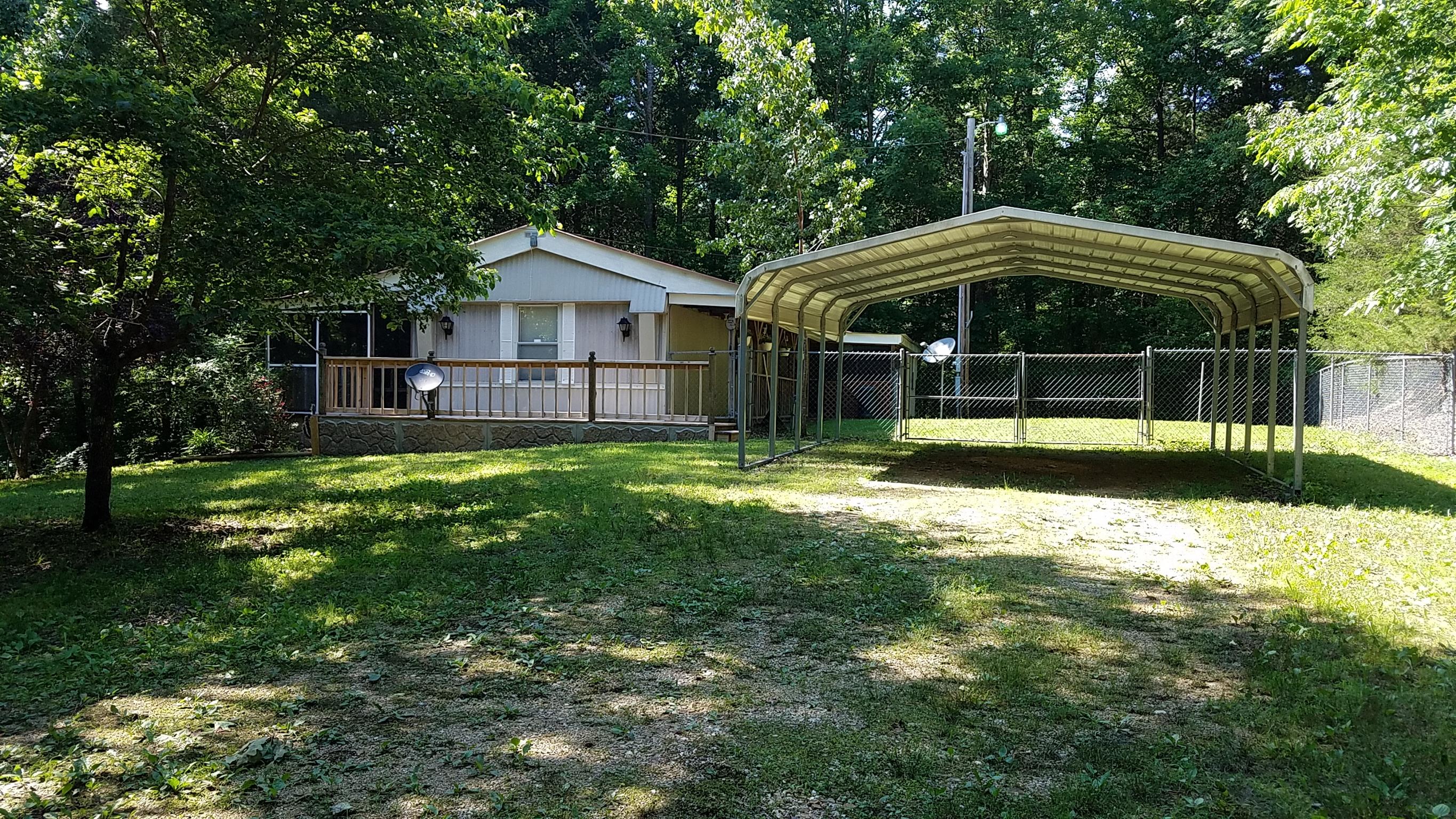 7128 Cuba Landing Road Waverly, TN 37185 - Photo 2 of 13 Side facing the road - 18 x 20 carport, shade trees, landscaping