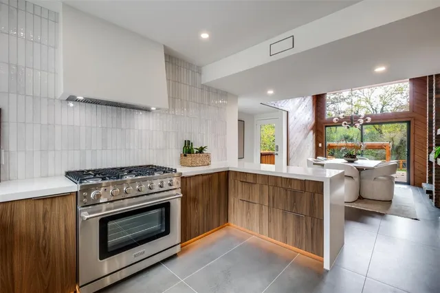 a kitchen with stainless steel appliances a sink a stove a refrigerator and white cabinets with wooden floor