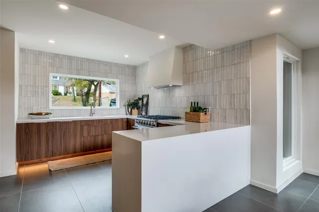 a large kitchen with stainless steel appliances a large counter top and a refrigerator