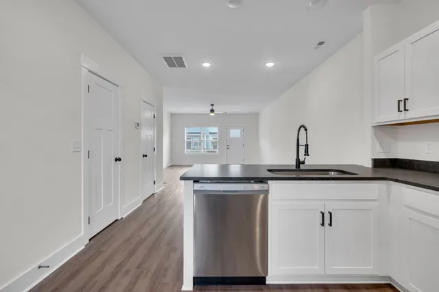 a kitchen with granite countertop a sink cabinets and wooden floor