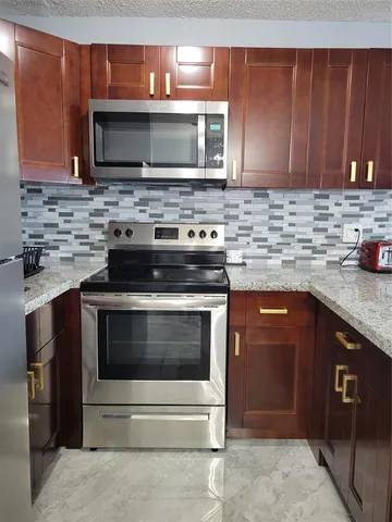 a kitchen with granite countertop wooden cabinets and stainless steel appliances