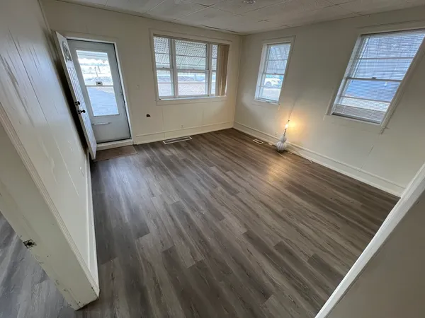 a view of an empty room with wooden floor and a window