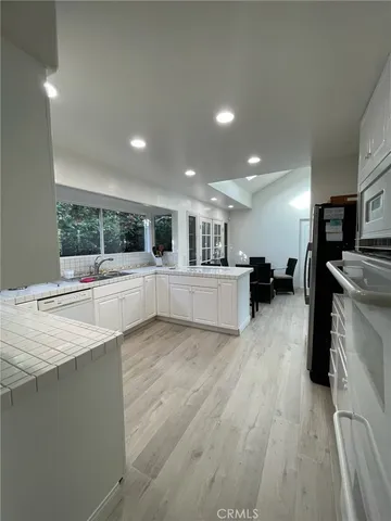 a view of a kitchen with a sink and dishwasher a refrigerator with wooden floor