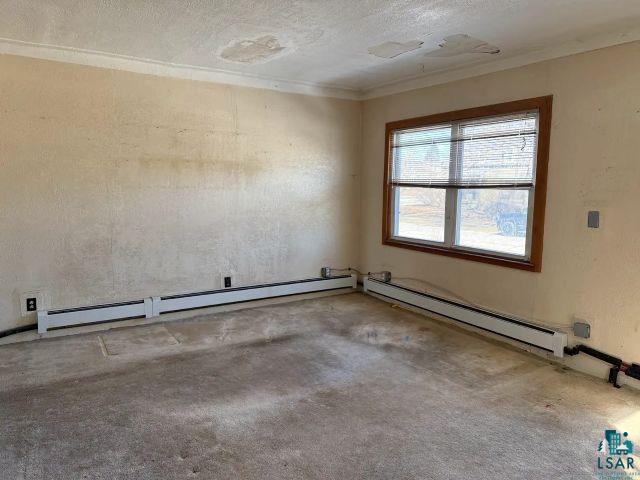 526 South 12th Street Virginia, MN 55792 - Photo 7 of 17 Spare room featuring a baseboard heating unit, a textured ceiling, and crown molding
