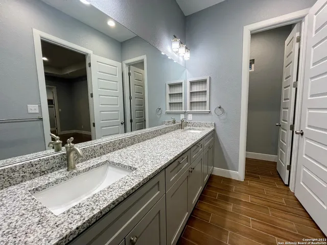 a bathroom with a granite countertop double vanity sink and a mirror