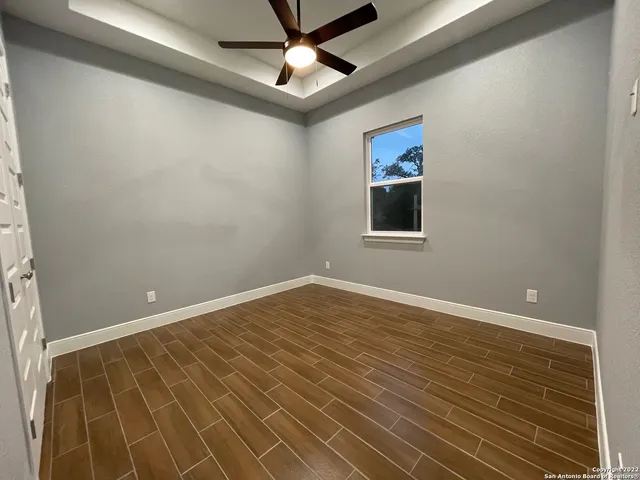en empty room with wooden floor and fan