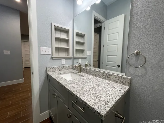 a bathroom with a granite countertop sink and a shower