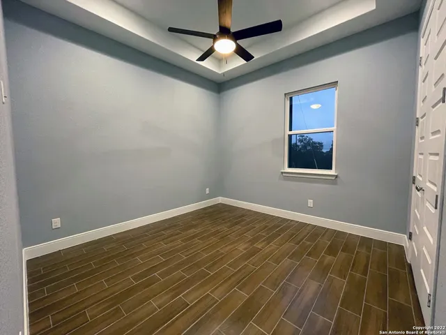 a view of an empty room with a chandelier fan and a window