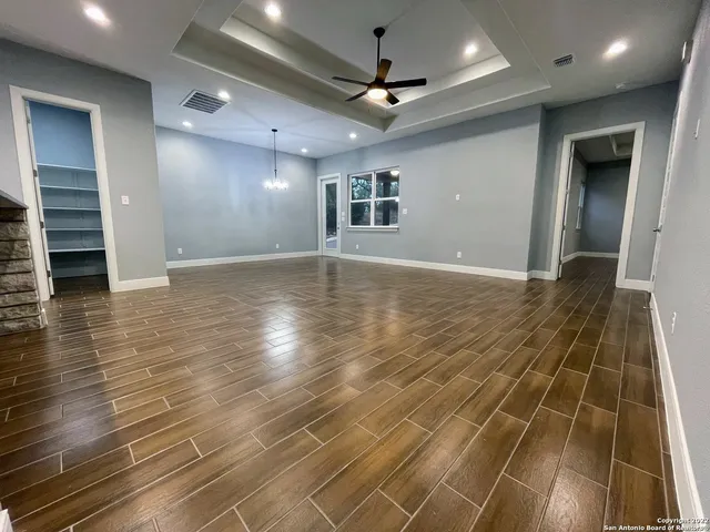 an empty room with wooden floor and ceiling fan