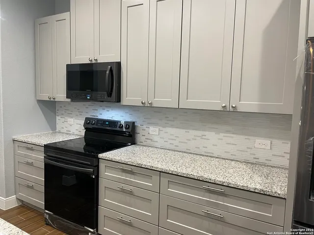a kitchen with granite countertop white cabinets and black appliances
