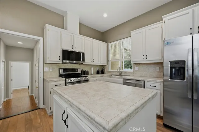 a kitchen with granite countertop a refrigerator stove a sink and dishwasher with wooden floor