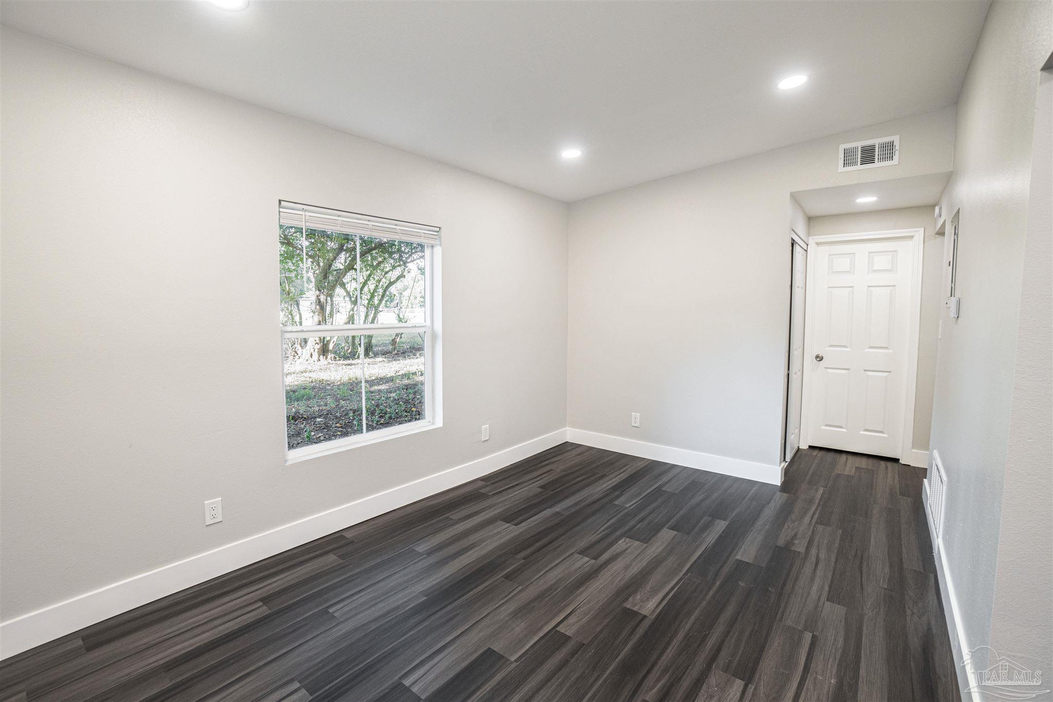 426 Forrest Street Cantonment, FL 32533 - Photo 1 of 25 an empty room with wooden floor and windows