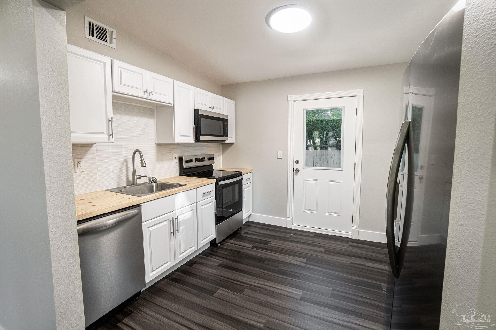 426 Forrest Street Cantonment, FL 32533 - Photo 3 of 25 a kitchen with a sink a refrigerator a window and cabinets