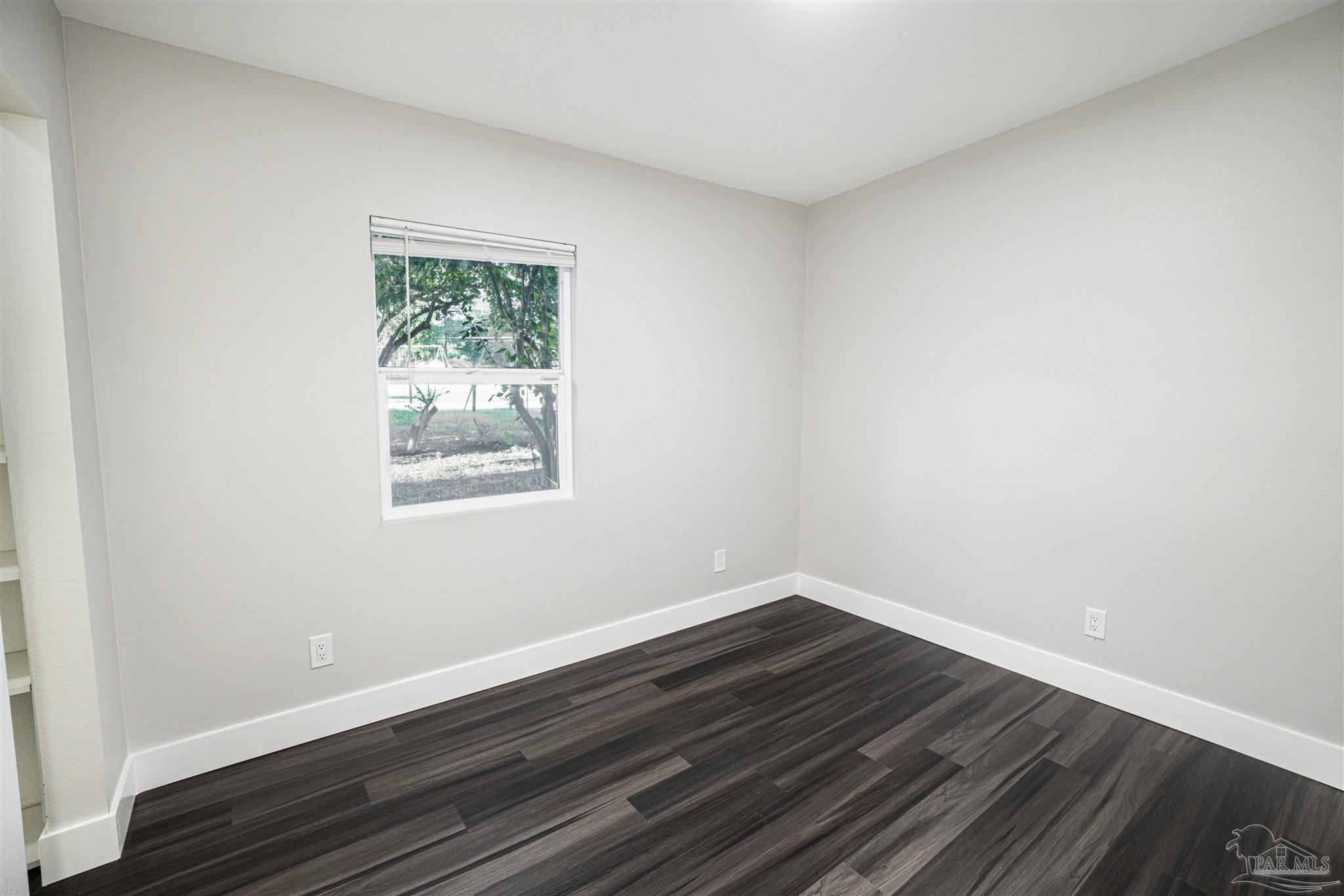 426 Forrest Street Cantonment, FL 32533 - Photo 10 of 25 a view of an empty room with wooden floor and a window