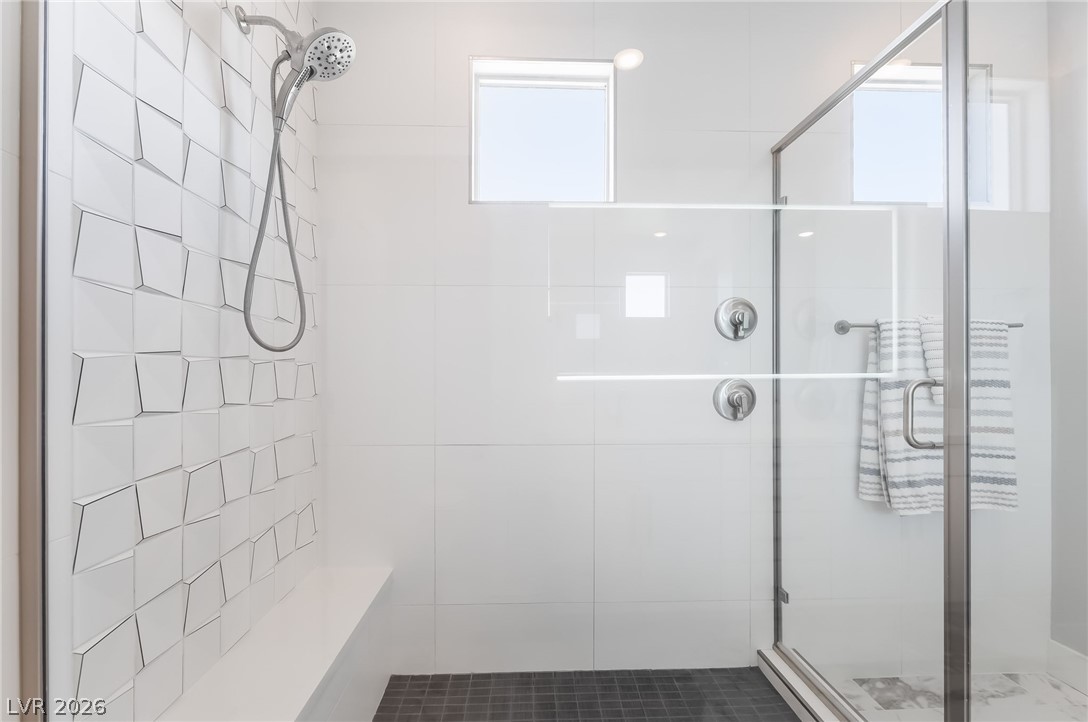 2166 Trivero Street Henderson, NV 89044 - Photo 30 of 61 Modern shower design with textured wall tiles and a practical built-in bench.