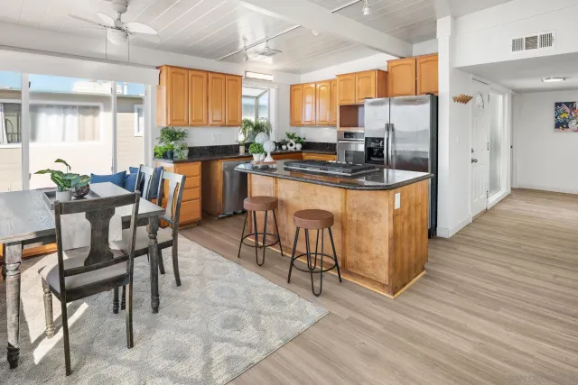 a kitchen with stainless steel appliances kitchen island granite countertop wooden cabinets a dining table and chairs