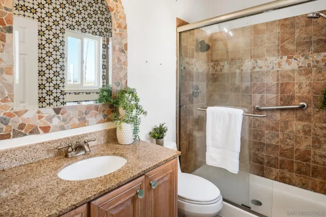 a bathroom with a granite countertop sink toilet and shower