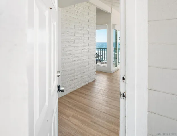 a view of a hallway with wooden floor and a bathroom