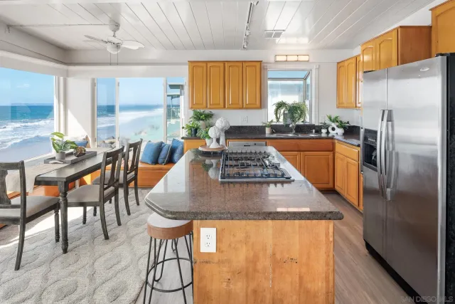 a kitchen with stainless steel appliances granite countertop a stove a refrigerator a kitchen island a dining table and chairs with wooden floor