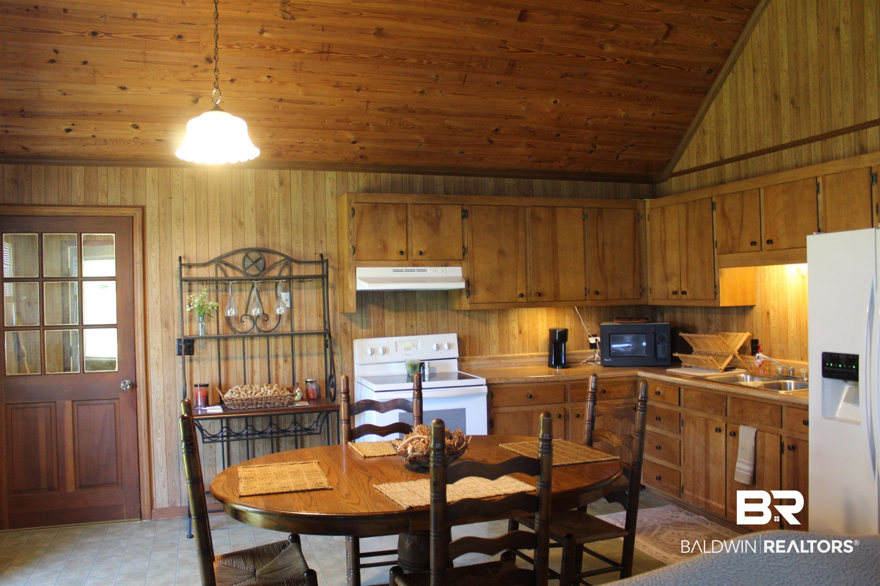6447 Henderson Road Lowndesboro, AL 36752 - Photo 12 of 22 Kitchen featuring white appliances, light countertops, wooden walls, wood finish cabinets, and a vaulted wooden ceiling