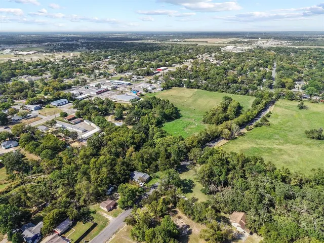an aerial view of residential houses with outdoor space and trees