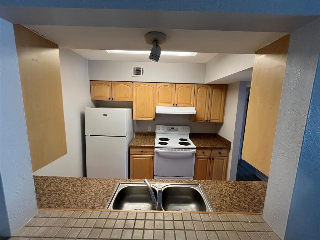 7000 Creswell Road, Unit 223 Shreveport, LA 71106 - Photo 10 of 16 Kitchen featuring a sink, under cabinet range hood, visible vents, white appliances, and dark countertops
